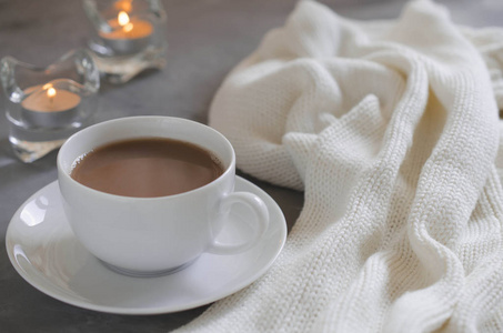 客厅内部的静物细节。 桌子上的一杯可可，蜡烛和编织的毯子。 舒适的秋冬概念。