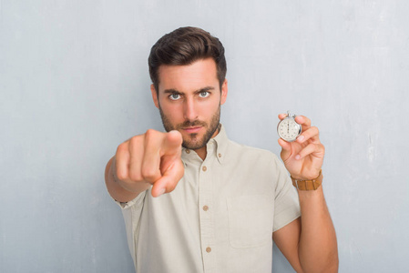 从前的时间一个英俊的年轻人站在灰色的墙上,手里拿着秒表,用手指指着