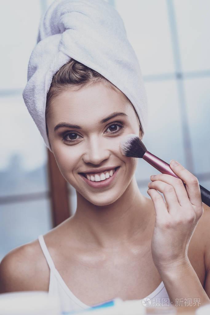 年轻女子在她的脸颊上涂上脸红