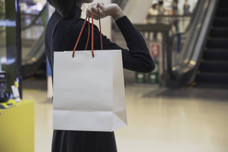 年轻的亚洲女人在购物中心拿着购物袋。购物概念。