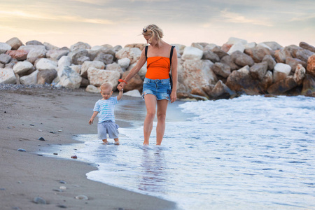 母亲和儿子在日落海滩上行走