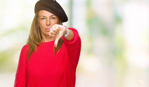 中年成年女性穿着时尚贝雷帽在孤立的背景上看起来不开心和愤怒，表现出拒绝和消极的拇指向下的手势。 不好的表情。