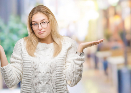 年轻的高加索女人戴着眼镜，在孤立的背景上毫无头绪，表情混乱，举起手臂和手。 怀疑概念。