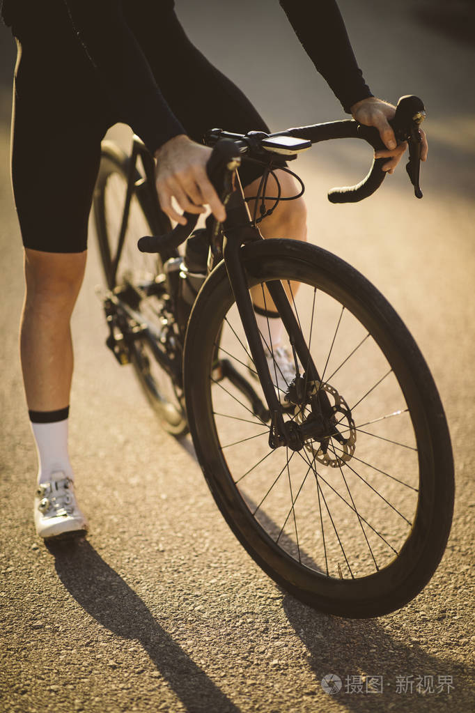 专业道路自行车赛车手摆姿势日落时男人骑山路自行车