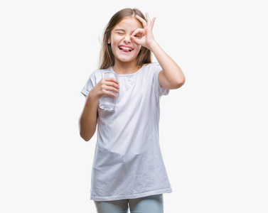 年轻漂亮的女孩喝着一杯水，在孤立的背景上，快乐的脸，微笑，做着好的标志，用手盯着手指看