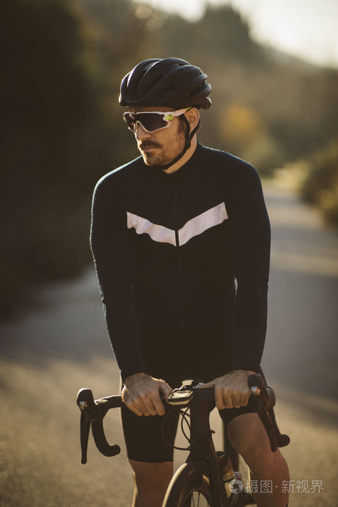 专业道路自行车赛车手摆姿势日落时男人骑山路自行车