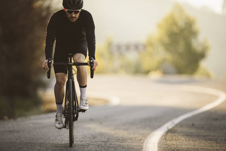专业道路自行车赛车在行动。 日落时，男人骑山路自行车。