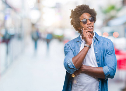 非洲美国人戴着耳机听音乐,在孤立的背景下思考,看起来疲惫,厌倦了