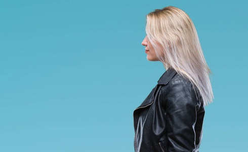 年轻的金发女人穿着黑色夹克,在孤立的背景上,看着侧面放松的轮廓