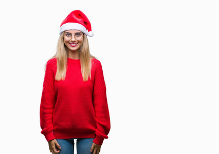 年轻漂亮的金发女人戴着圣诞帽，在孤立的背景上，脸上带着快乐和凉爽的微笑。 幸运的人。
