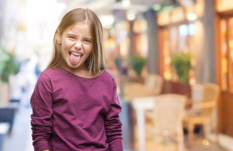 年轻漂亮的女孩在孤立的背景上伸出舌头,以有趣的表情高兴. 情感概念.