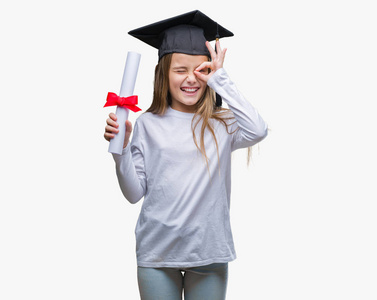 年轻漂亮的女孩戴着毕业帽，抱着学位，在孤立的背景下，快乐的脸，微笑，做着好的标志，用手盯着手指看。