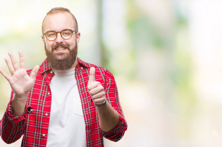 年轻的白种人臀部男子戴着眼镜，在孤立的背景上，显示和举着六个手指，同时微笑自信和快乐。