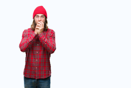 年轻的英俊男子，长发，戴着红色的帽子，在孤立的背景上震惊地用手捂住嘴，因为错误。 秘密概念。