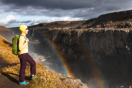 一个年轻的女人站在欧洲最强大的瀑布落水的岸边。 Jokulsarglufur国家公园冰岛丰富多彩的夏日
