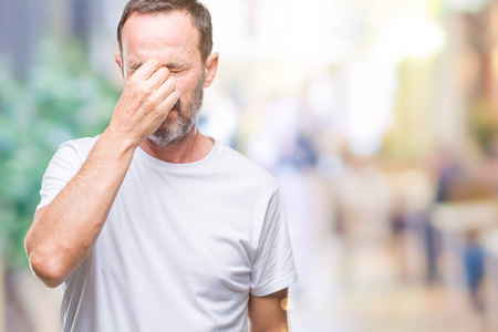 老年人眼睛疲劳的图片中年老人穿着白色t恤,在孤立的背景下疲惫地揉着