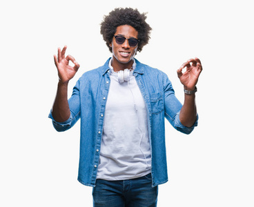 美国黑人男子戴着耳机听音乐，在孤立的背景下放松，微笑，闭着眼睛，用手指做冥想手势。 瑜伽概念。