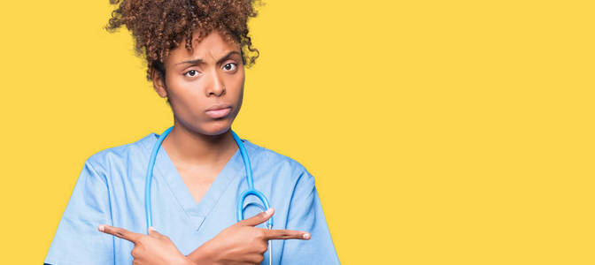 年轻的非裔美国医生女人，在孤立的背景下，指着两边，手指不同的方向，不同意