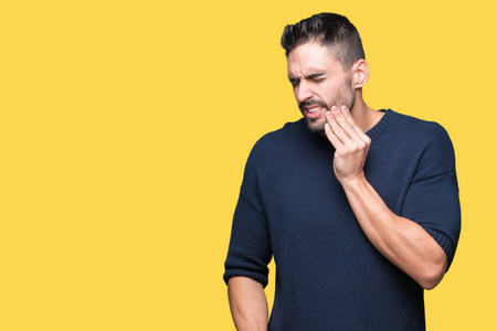 年轻的帅哥穿着毛衣,在孤立的背景上,用手摸嘴,因为牙痛或牙齿上的