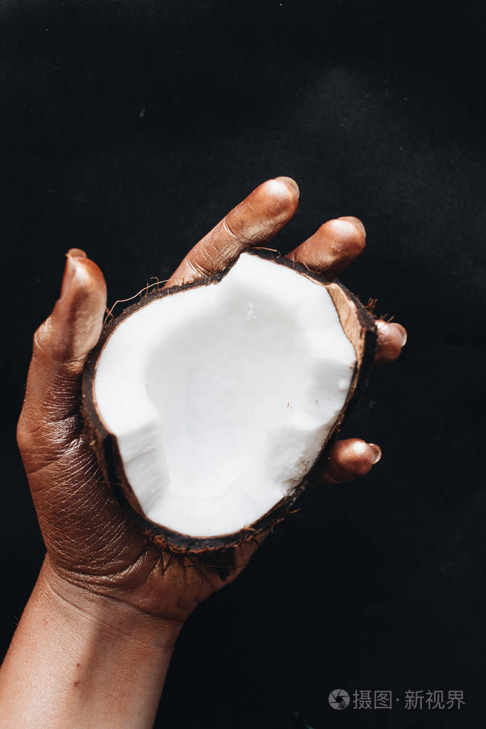 黑色背景下握着椰子的雌手