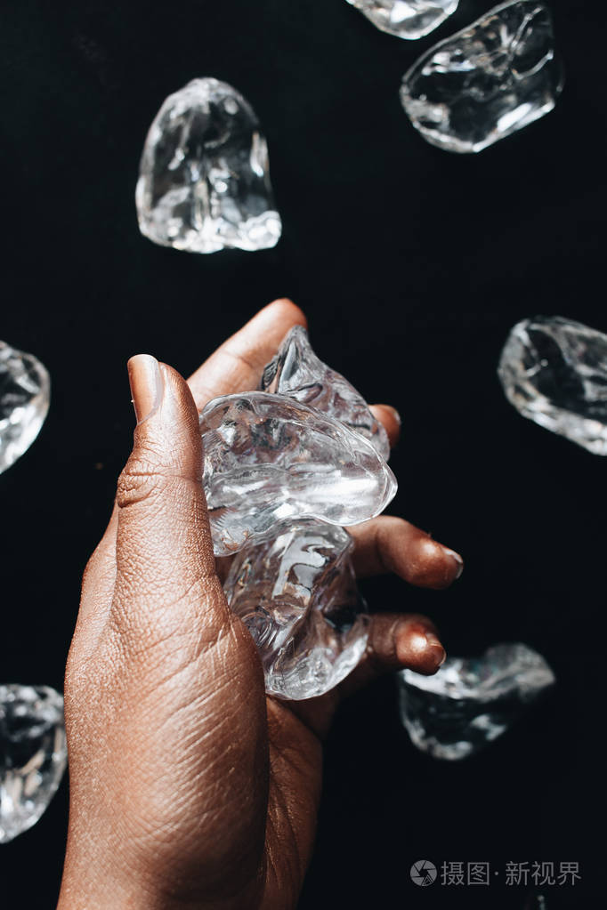黑色背景下的女性手和冰块