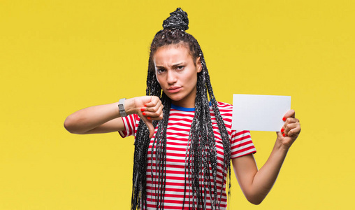 年轻的非裔美国女孩拿着空白卡在孤立的背景上，愤怒的脸，消极的标志，表示不喜欢，竖起大拇指拒绝概念