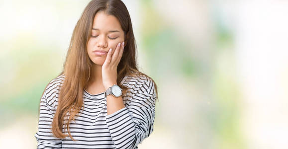 年轻漂亮的黑发女人穿着条纹毛衣，在孤立的背景下思考，看起来疲惫，厌倦了交叉双臂的抑郁问题。