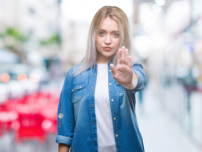 年轻的金发女人在孤立的背景下做停止用手掌唱歌。 警告表情，脸上有负面和严肃的手势。