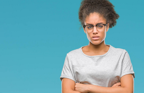 年轻的非洲美国妇女戴着眼镜，在孤立的背景怀疑和紧张的不赞成的表情在脸上交叉的手臂。 消极的人。