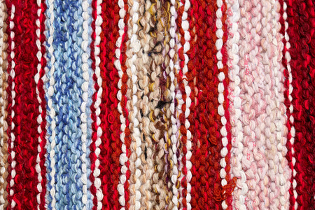 针织面料表面有不同的彩色条纹。背景特写纺织品复古地毯或地毯。织物的纹理与线条的几何形状相结合。手工制品