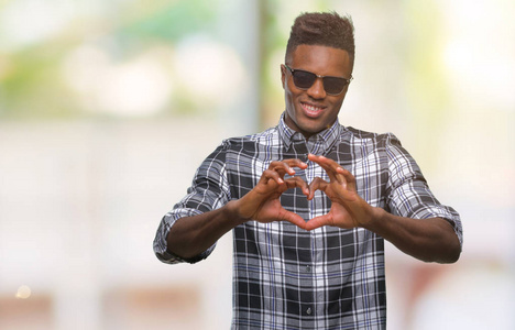 人戴着太阳镜,在孤独的背景下微笑,在爱中显示心脏的象征和形状与手