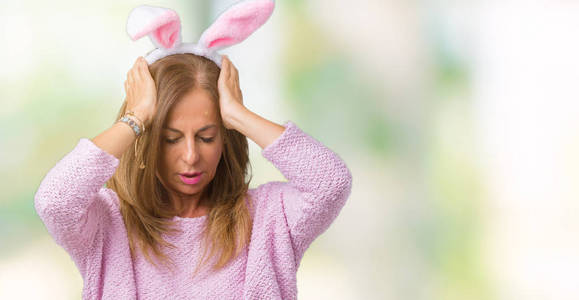 中年黑发妇女戴着复活节兔子耳朵，在孤立的背景下，患有头痛，绝望和压力，因为疼痛和偏头痛。手放在头上。