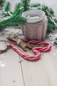 米色针织服装可可白杯。带圣诞树的白色木制背景上的手套和红色焦糖糖果空间供文字使用