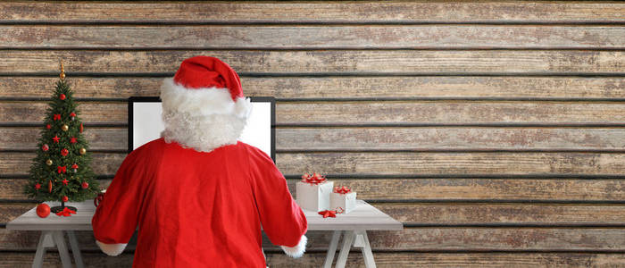 圣诞老人在网上发送贺卡。在木墙旁边复制空间。