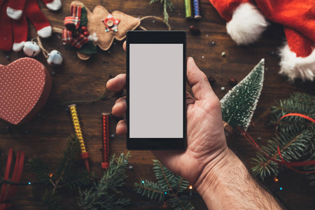 智能手机手中的圣诞季节模拟与节日装饰的背景。
