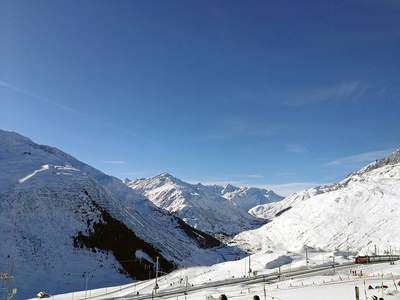 瑞士火车站在白雪覆盖的山丘之间，阳光明媚。 瑞士冰川快递公司。