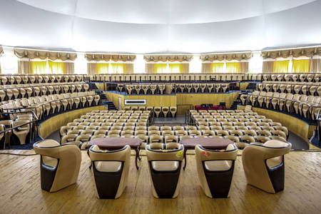 现代音乐厅明亮的内部，有一个舞台和一排排舒适的皮革椅子，一个舞台和声学放大系统，在自然光下准备演示