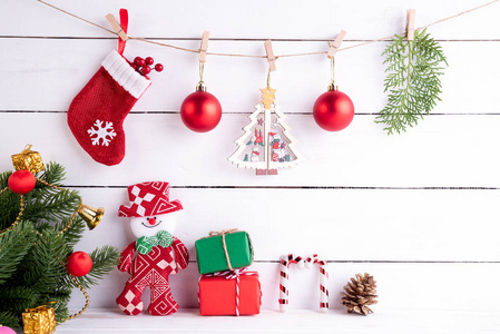 圣诞节背景概念。 圣诞老人带着红色的木盒和白色的木制背景上的圣诞树，袜子和红色浆果，云杉枝和雪人挂在绳子上。