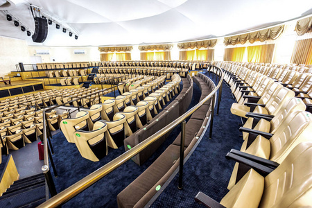 现代音乐厅明亮的内部，有一个舞台和一排排舒适的皮革椅子，一个舞台和声学放大系统，在自然光下准备演示