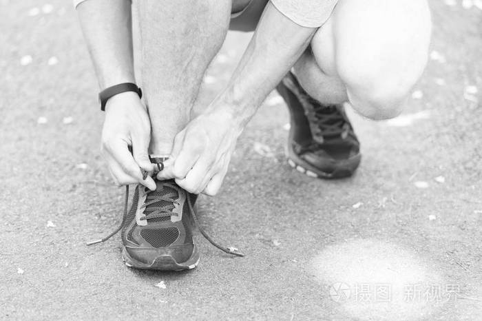 运动员的手与步进器捆绑鞋带运动运动鞋.运行设备的概念.男性手系鞋带