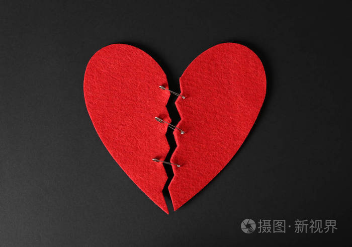 切割毛毡心的一半与黑色背景顶部视图上的引脚连接