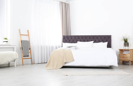 宽敞舒适的床在时尚的房间里。 公寓室内设计