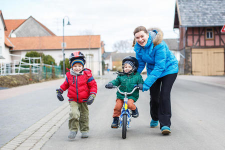 母亲教她两岁的儿子骑自行车