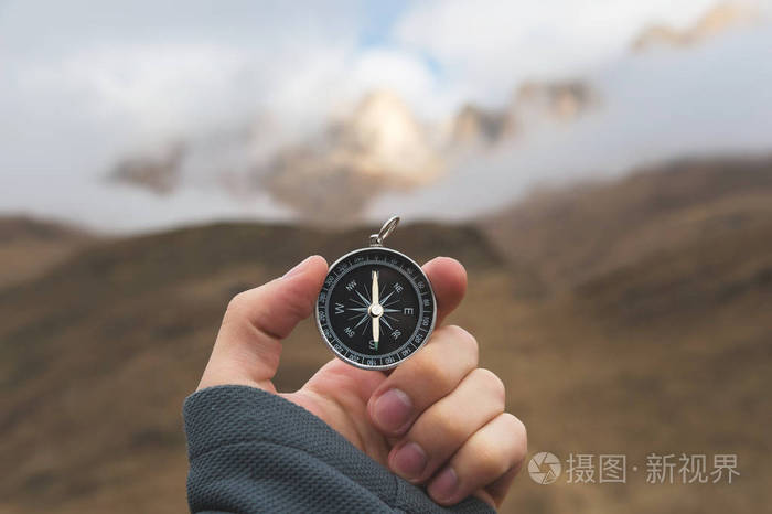 一名男性徒步者正在寻找秋天山区有磁罗盘的方向视点拍摄拿着手表手镯