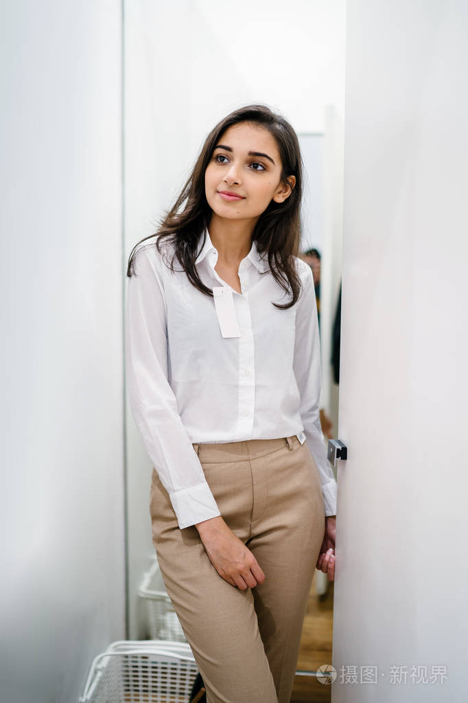 一位年轻美丽的印度亚洲妇女在商场时装店的试衣间试穿新衣服的肖像.