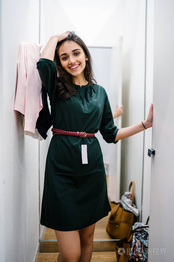 一位年轻美丽的印度亚洲妇女在商场时装店的试衣间试穿新衣服的肖像.