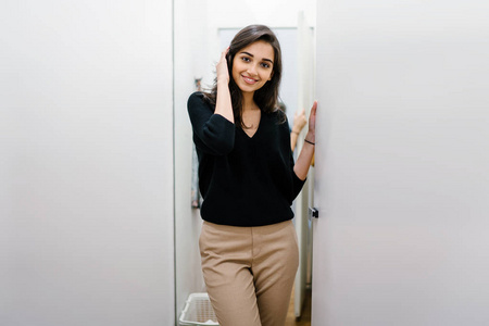 一位年轻美丽的印度亚洲妇女在商场时装店的试衣间试穿新衣服的肖像.