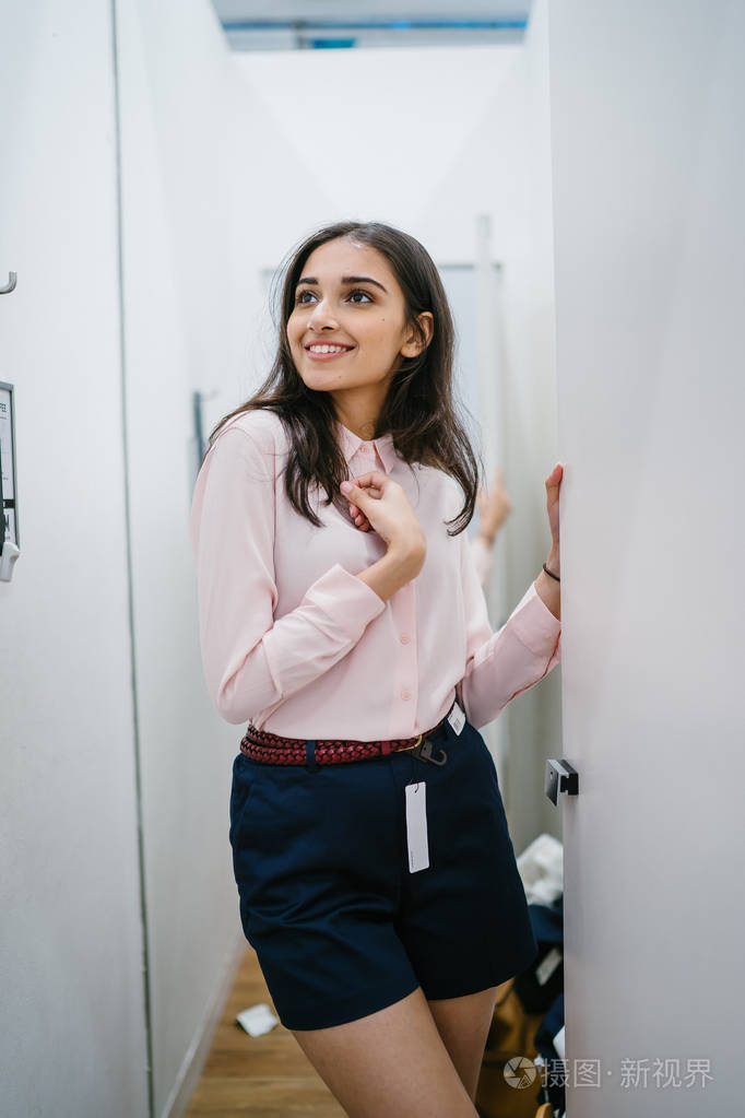 一位年轻美丽的印度亚洲妇女在商场时装店的试衣间试穿新衣服的肖像.