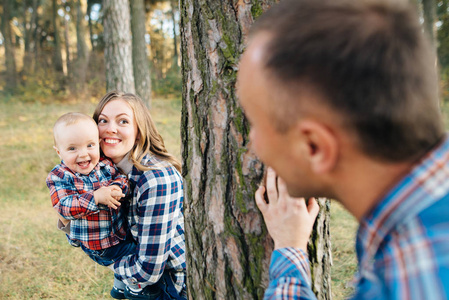 一个可爱的家庭，爸爸妈妈和儿子在一个美丽的松林里户外玩。