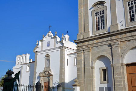天主教堂诺萨森霍拉多卡莫位于葡萄牙塔维拉阿尔加维老城，前景是一座历史建筑。